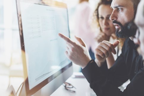 People looking intently at a computer screen, reviewing data or test results.